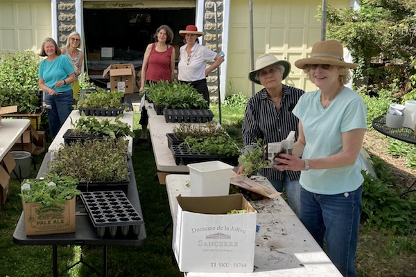 CP&GC members planting native plants in containers outside, smiling at the camera.